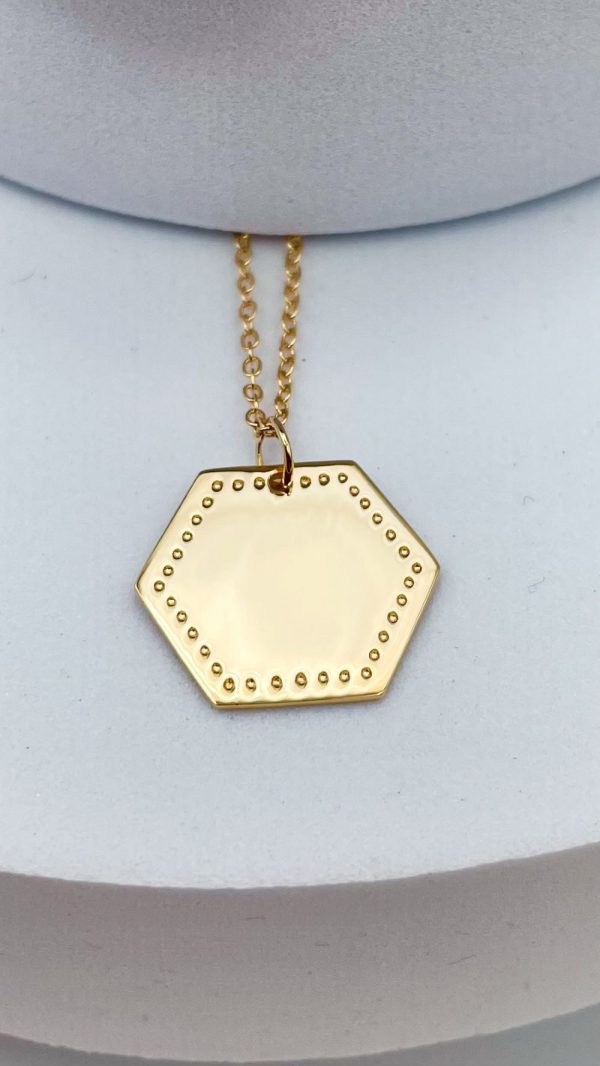 Zoom sur médaille hexagonale à graver en plaqué or avec motifs pointillés, bijou à message