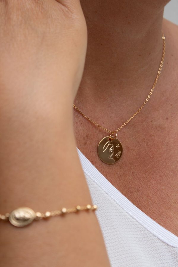 Zoom sur le collier Vierge Marie Fiat en plaqué or, porté par une femme avec bracelet assorti