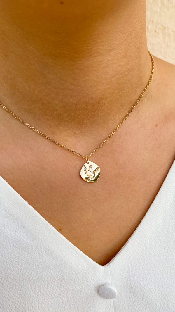 Collier colombe de la paix en plaqué or porté au cou, sur fond de blouse blanche