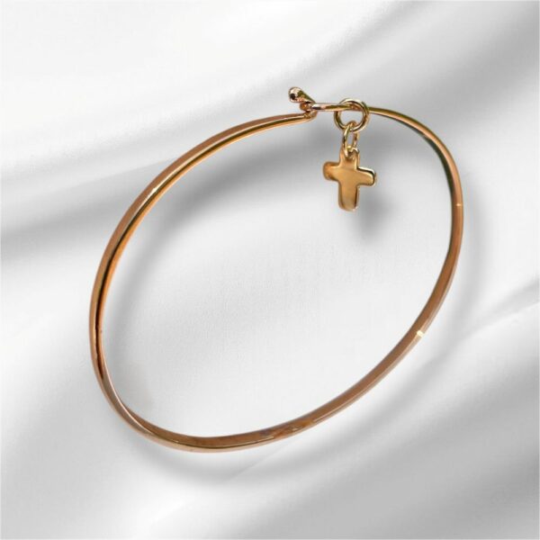 Jonc doré avec croix suspendue sur fond blanc soyeux – bijou religieux élégant