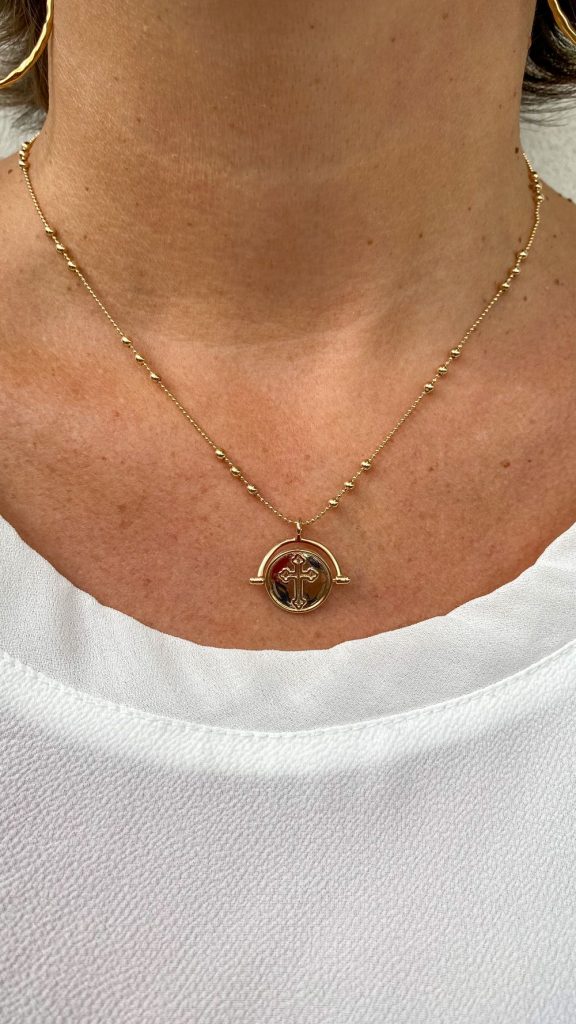 Collier médaille croix en plaqué or posé sur tissu dentelle, bijou spirituel féminin et délicat