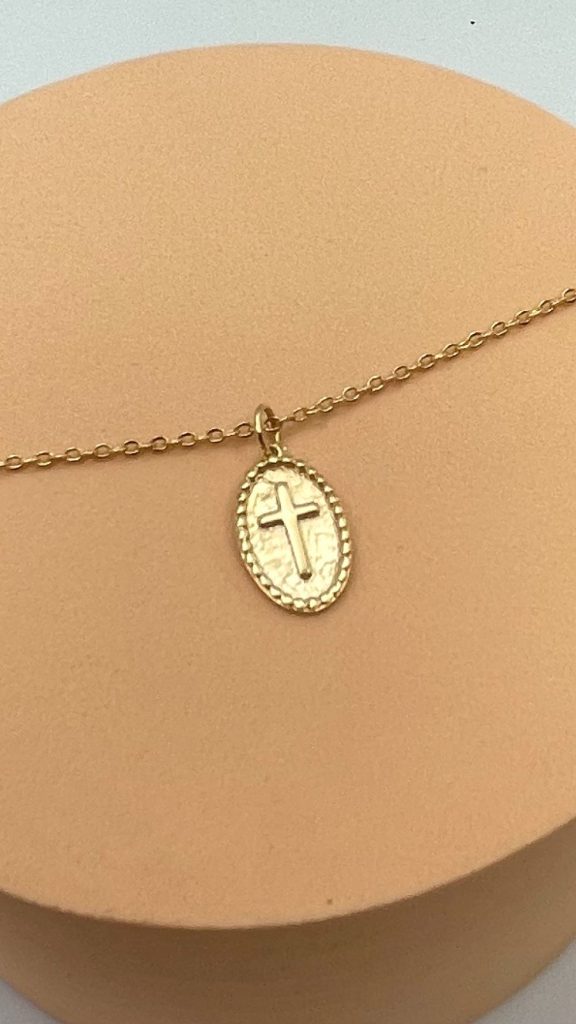 Collier religieux en plaqué or avec médaille croix, vue rapprochée sur fond rosé