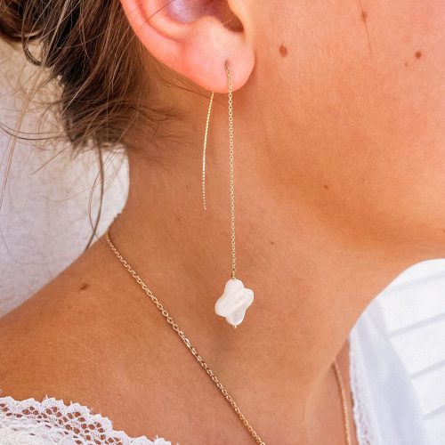 Femme portant des boucles d'oreilles pendantes en nacre blanche et plaqué or de la Collection Blanche pour mariage et cérémonie.